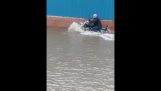 Überqueren Sie eine überflutete Straße auf einem Motorrad