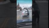 Гай очищает заднее стекло переднего автомобиля от снега