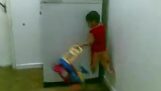 Pieni poika kiipeää jääkaapilla yhdellä kädellä