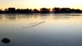Ein Stück Eis auf einen zugefrorenen See werfen