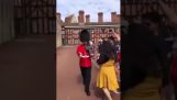 Muž z královské gardy tlačí ženu stojící na ulici
