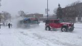 Three 4-wheel-drive vehicles pulling a bus that got stuck in the snow
