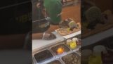 En restaurantbetjent sovner mens han lager en sandwich