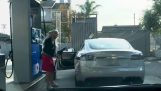 La blonde avec la voiture électrique à la station d'essence